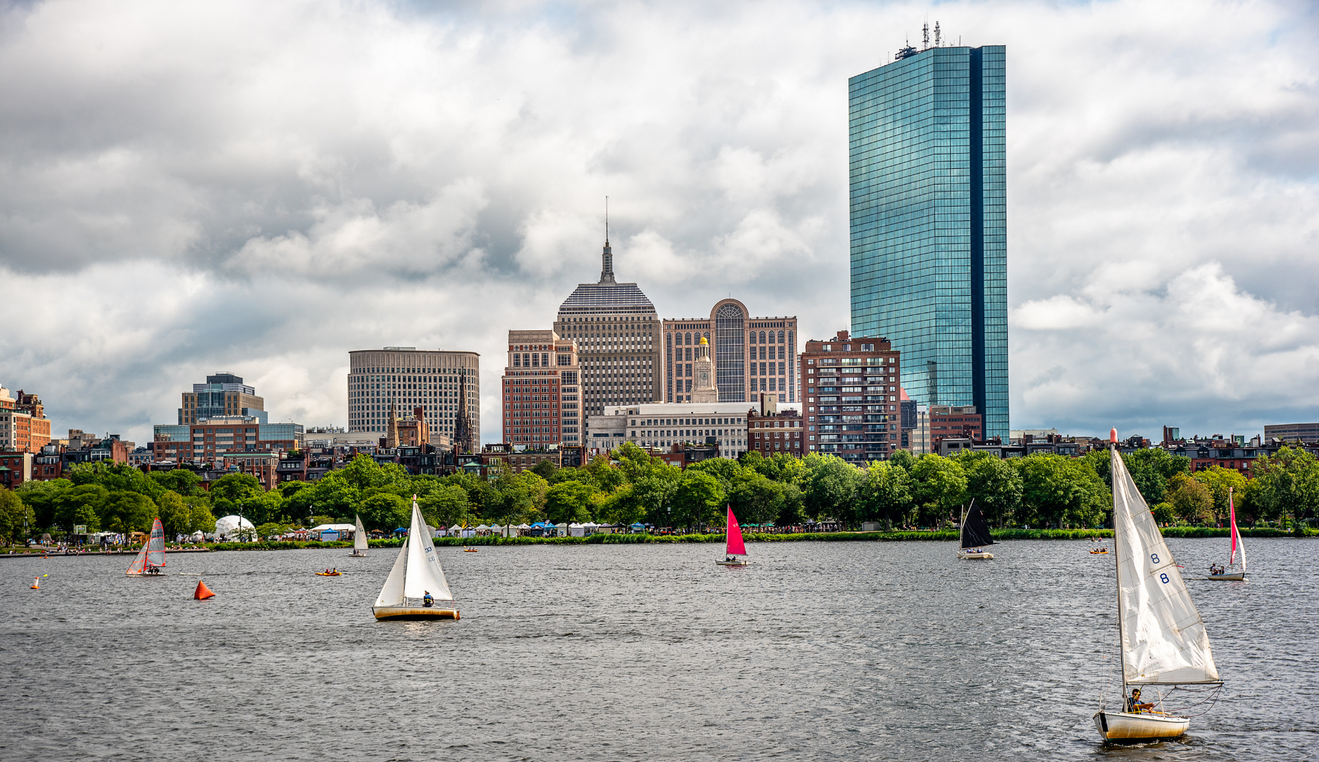 Blick auf die Skyline von Boston mit Segelbooten auf dem Charles River unter bewölktem Himmel