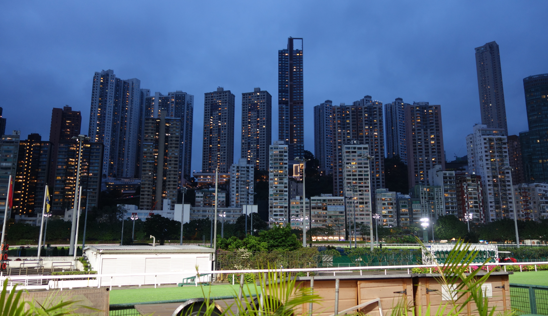 Happy Valley Pferderennen Hongkong in Hongkong während der blauen Stunde mit beleuchteten Hochhäusern der Skyline im Hintergrund