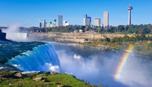 Blick auf die Niagarafälle mit Regenbogen und Skyline im Hintergrund
