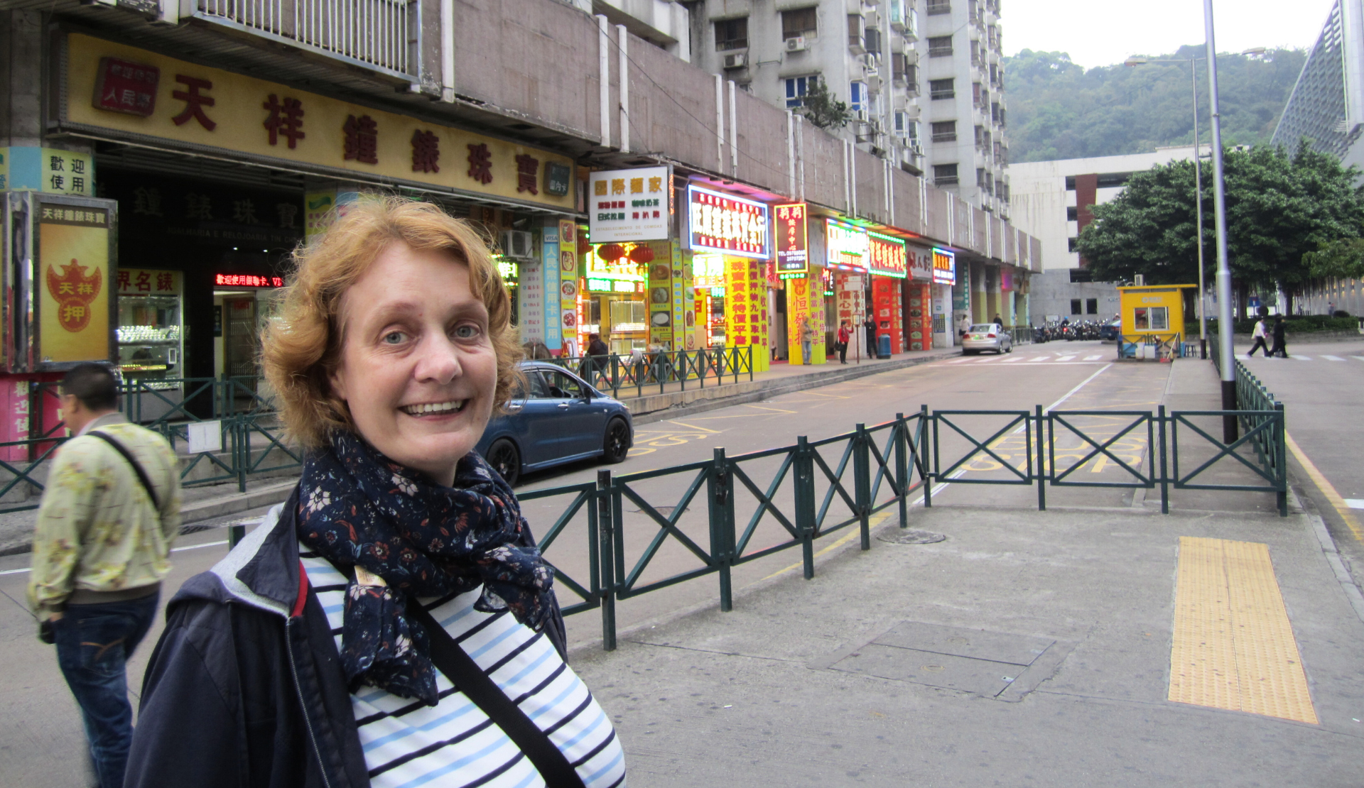Peggy in einer Straße in Macau mit bunten Geschäften im Hintergrund