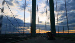Roadtrip USA über eine Hängebrücke bei Sonnenuntergang, Seile und Pylon im Gegenlicht