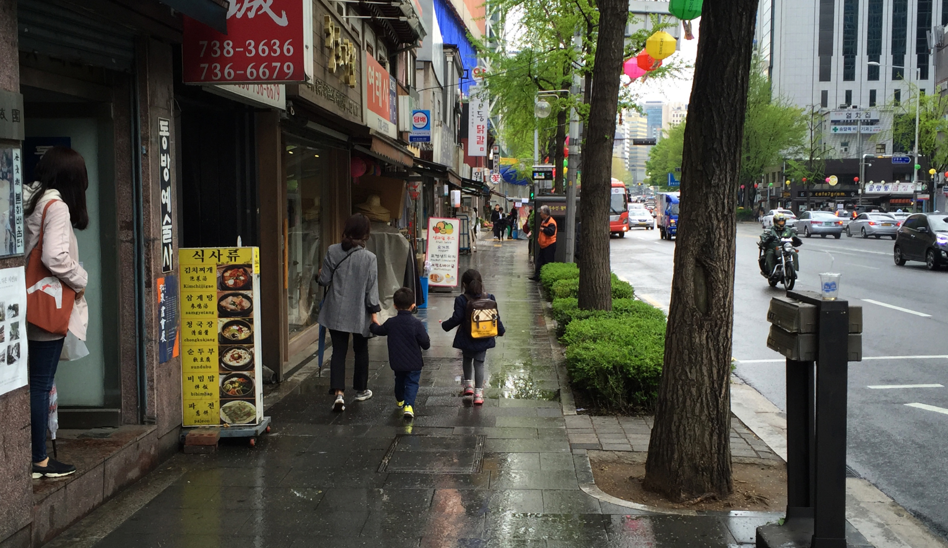 Frau läuft an Restaurants und Geschäften in einer Straße in Seoul vorbei
