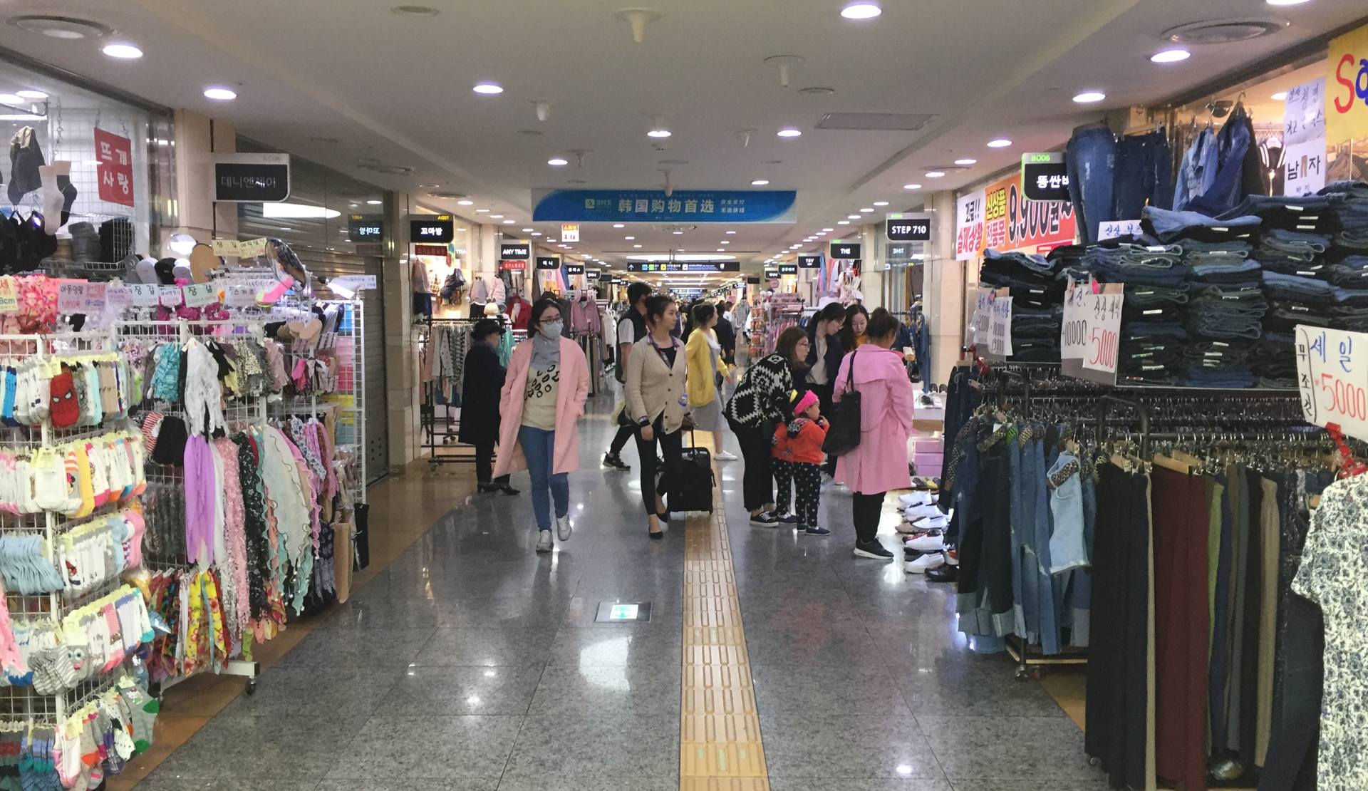 Unterirdische Shopping Mall in einer Metrostation in Seoul mit vielen Kleidungsgeschäften und Passanten