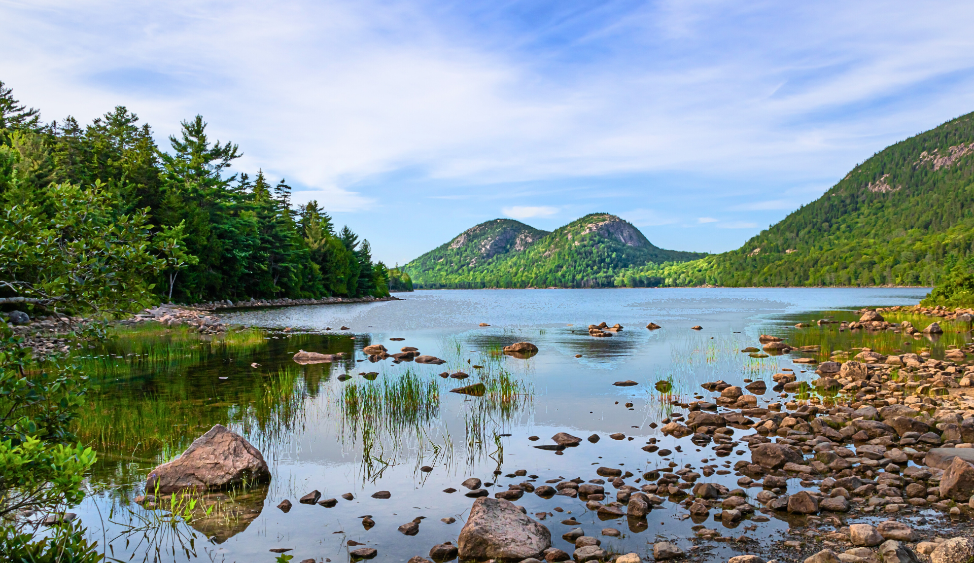 Jordan Pond im Acadia Nationalpark mit klarem Wasser, Steinen im Uferbereich und Bergen im Hintergrund