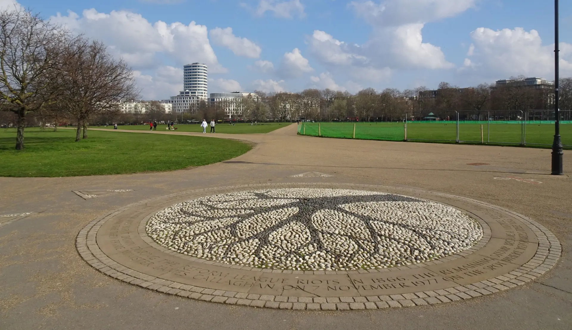 Weite Grünfläche im Hyde Park in London mit gepflastertem Weg