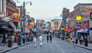 Menschen spazieren am Abend über die Beale Street in Memphis mit bunten Neonlichtern und Musikclubs