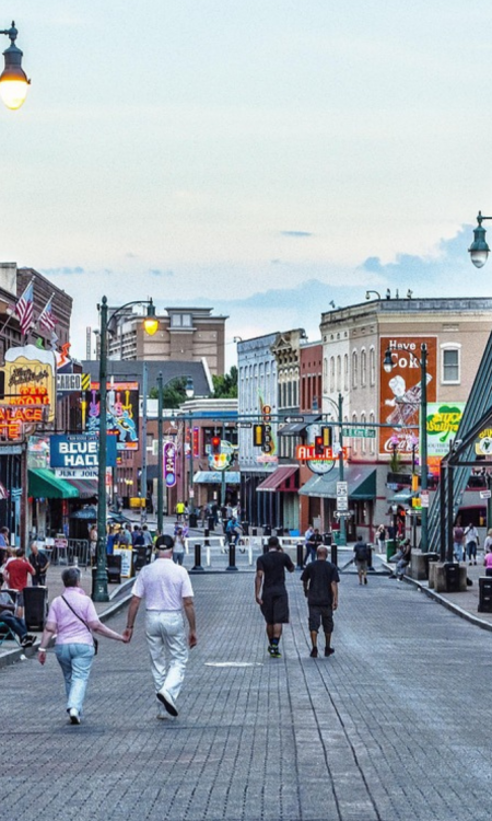 Menschen spazieren am Abend über die Beale Street in Memphis mit bunten Neonlichtern und Musikclubs