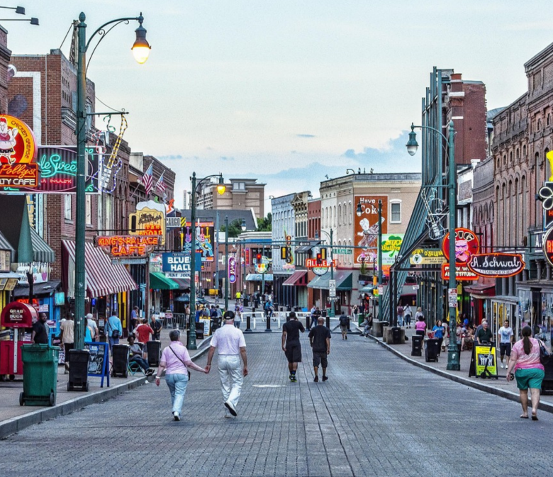 Menschen spazieren am Abend über die Beale Street in Memphis mit bunten Neonlichtern und Musikclubs