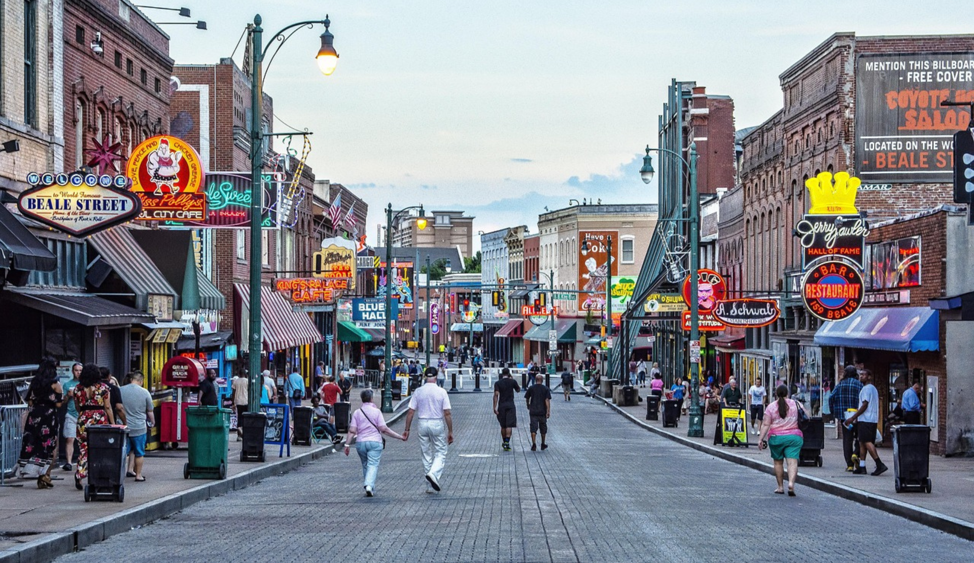 Menschen spazieren am Abend über die Beale Street in Memphis mit bunten Neonlichtern und Musikclubs