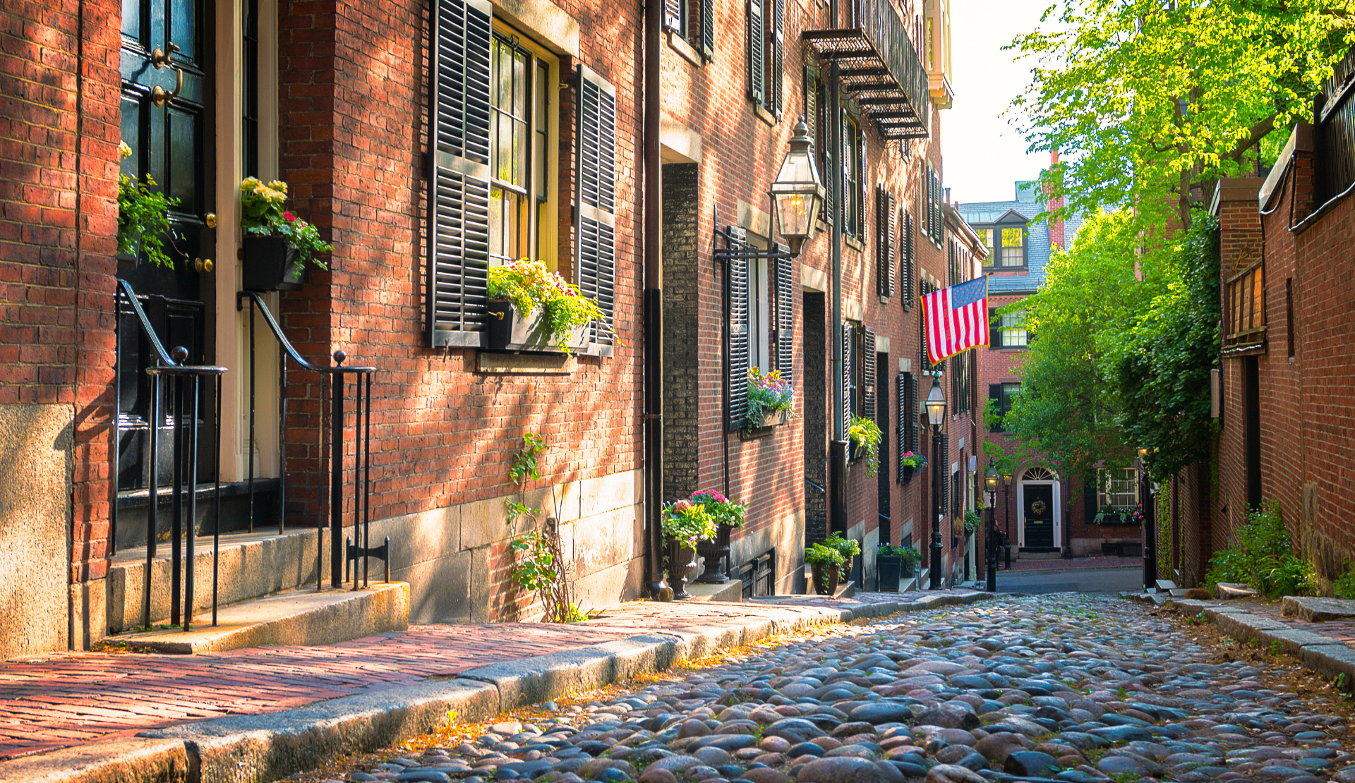 Kopfsteinpflasterstraße Acorn Street in Boston mit roten Backsteinhäusern und US-Flagge