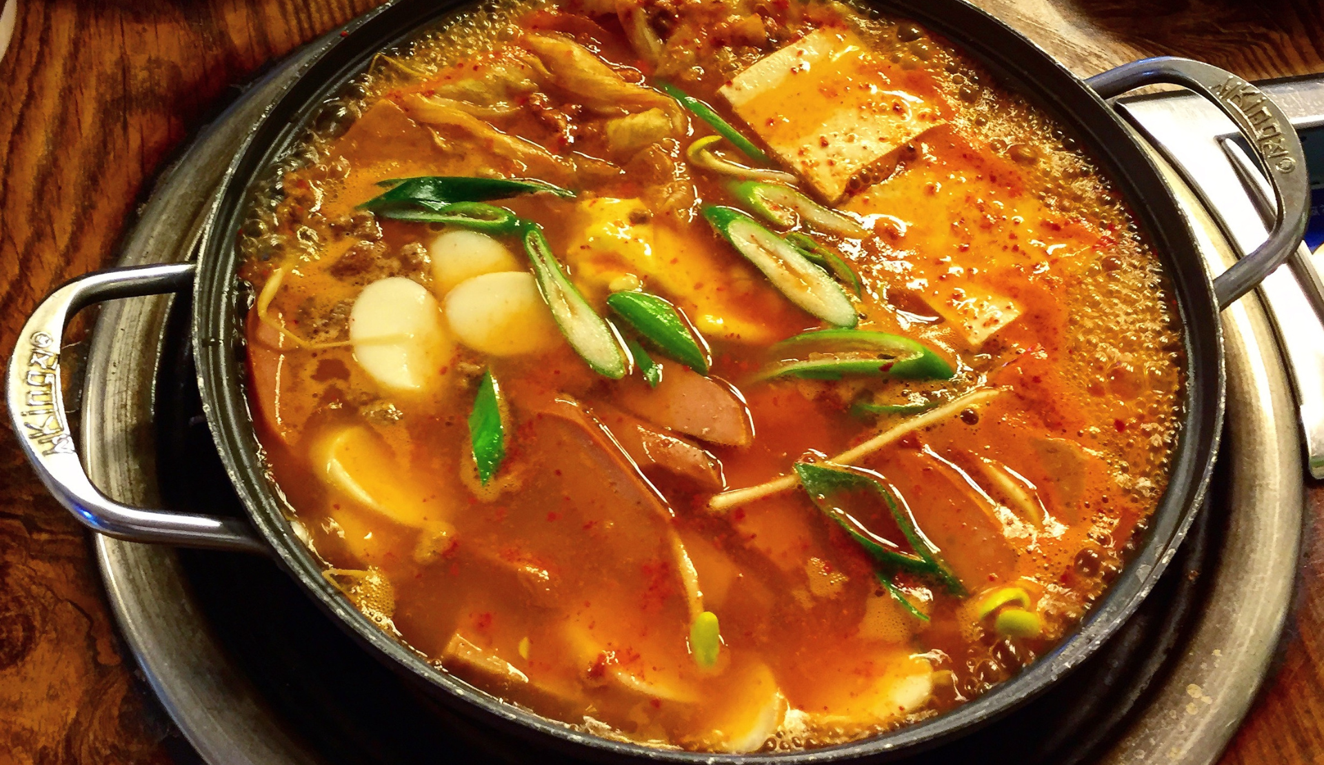 Budae-jjigae, koreanischer Army Stew, mit Tofu, Würstchen, Gemüse und scharfer roter Brühe in einem Topf
