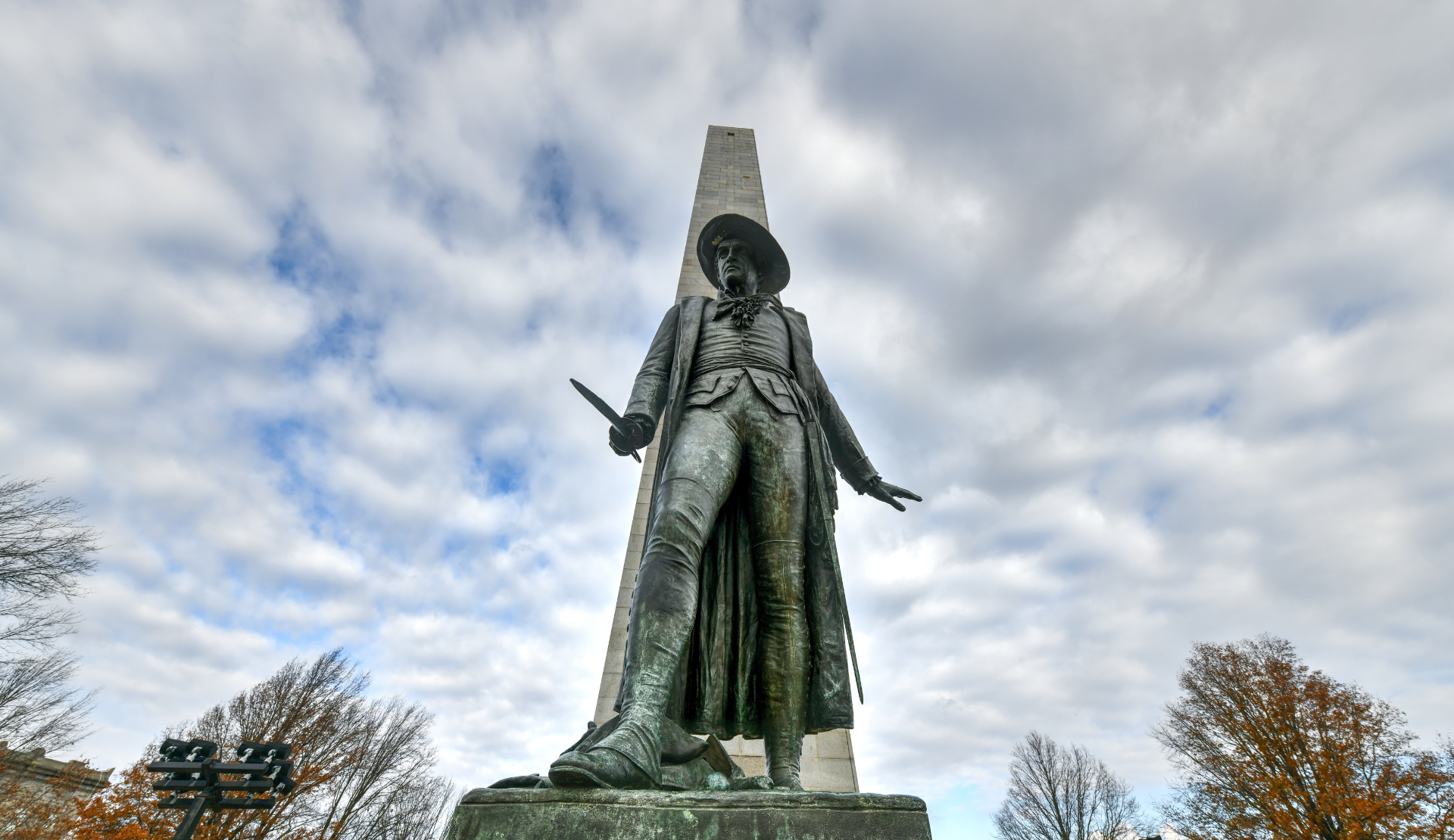 Statue am Bunker Hill Monument in Boston mit Obelisk und bewölktem Himmel
