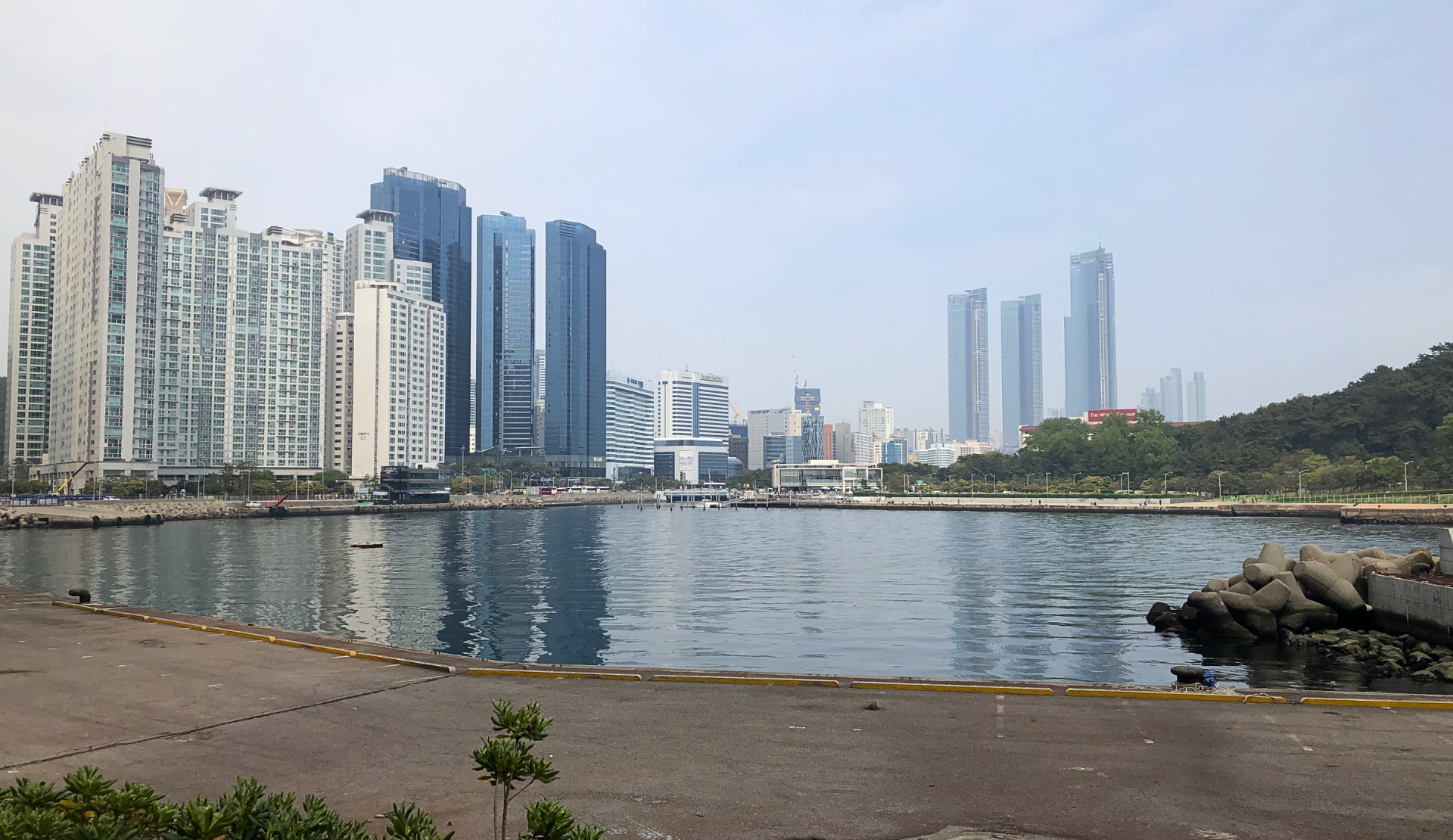 Hafen von Busan Südkorea mit modernen Hochhäusern und Wellenbrecher im Vordergrund