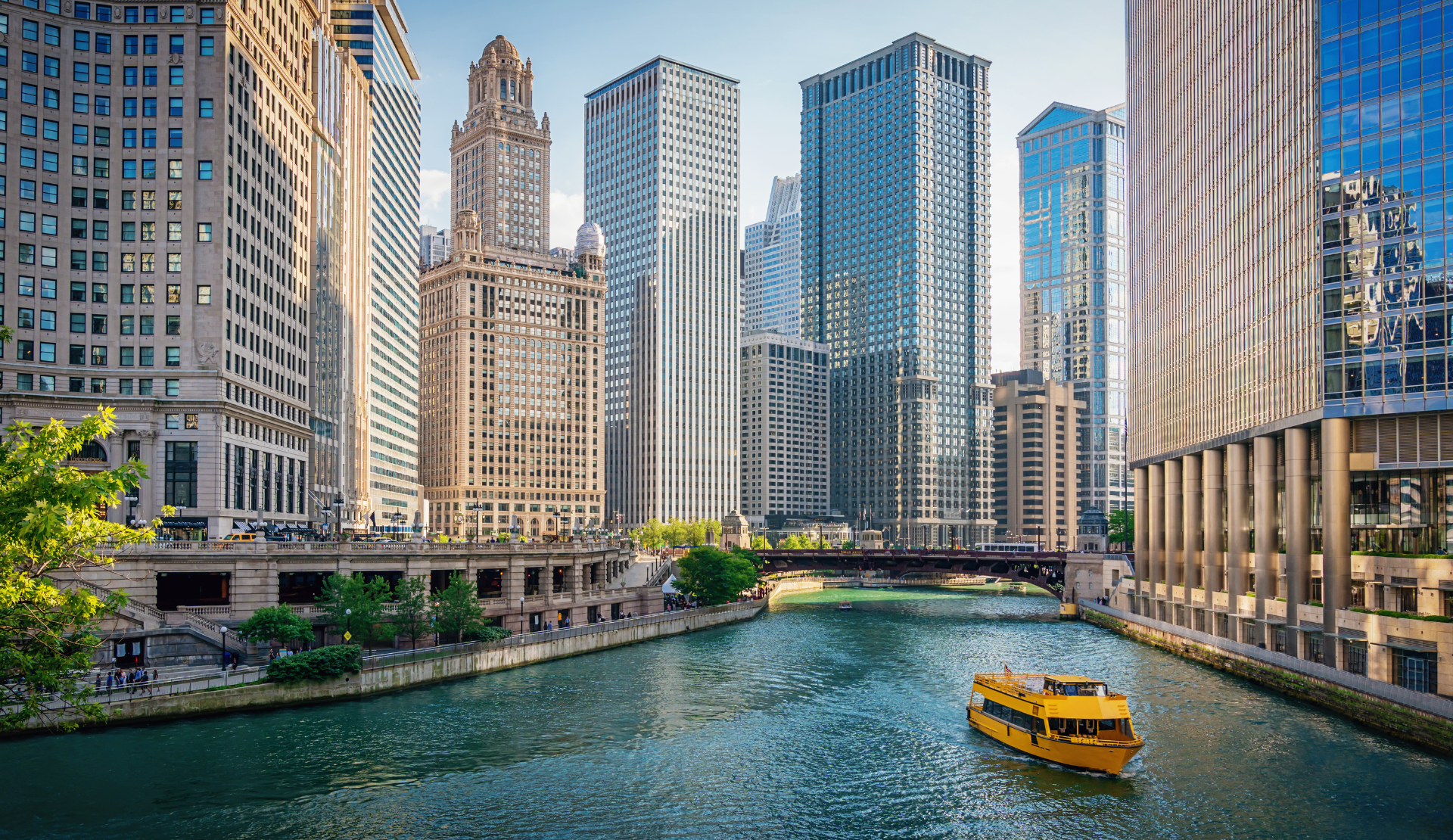 Blick auf den Chicago River mit Wolkenkratzern und moderner Architektur in Downtown Chicago, ein gelbes Wassertaxi fährt auf dem Fluss