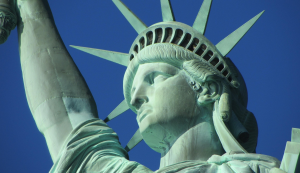 Detailaufnahme der Freiheitsstatue in New York mit erhobener Fackel vor blauem Himmel