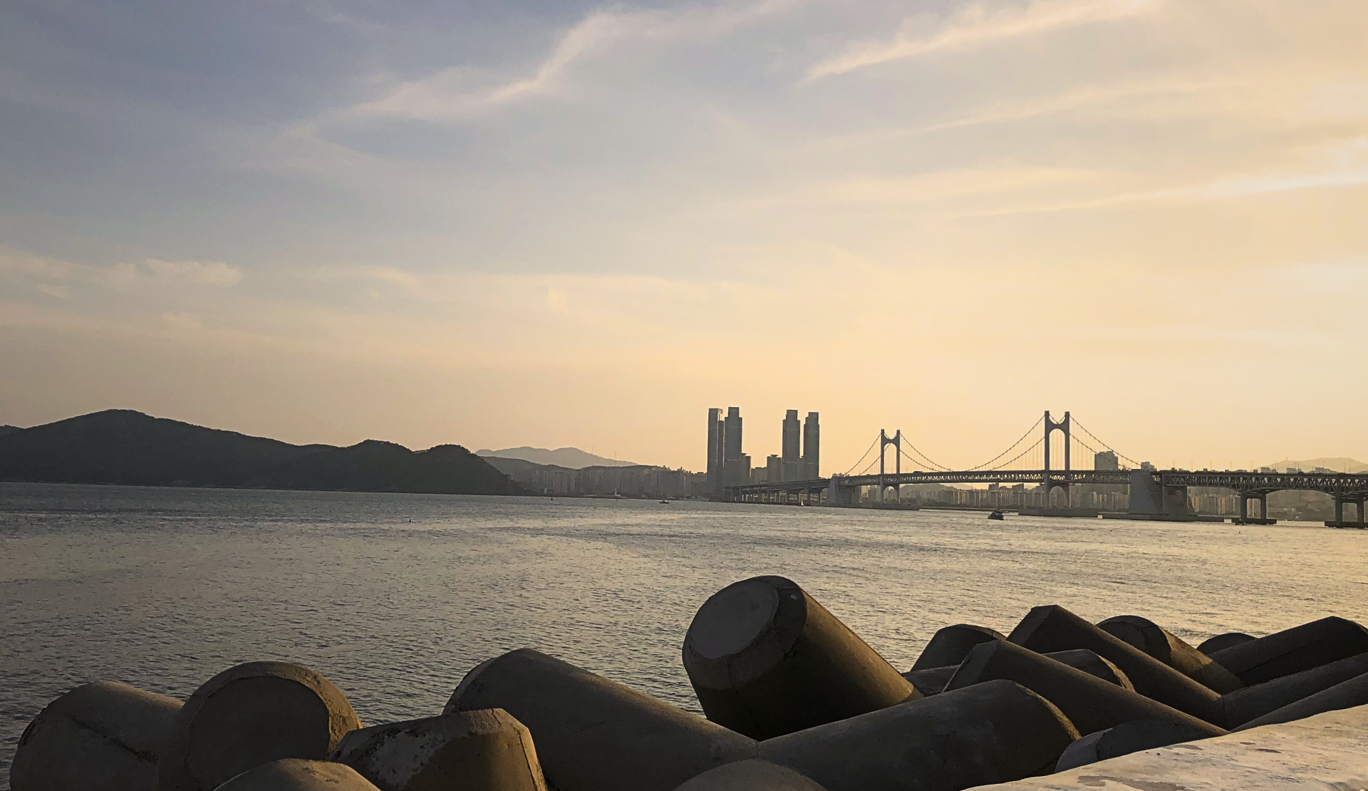 Gwangan-Brücke in Busan Südkorea im Abendlicht mit Wellenbrecher im Vordergrund