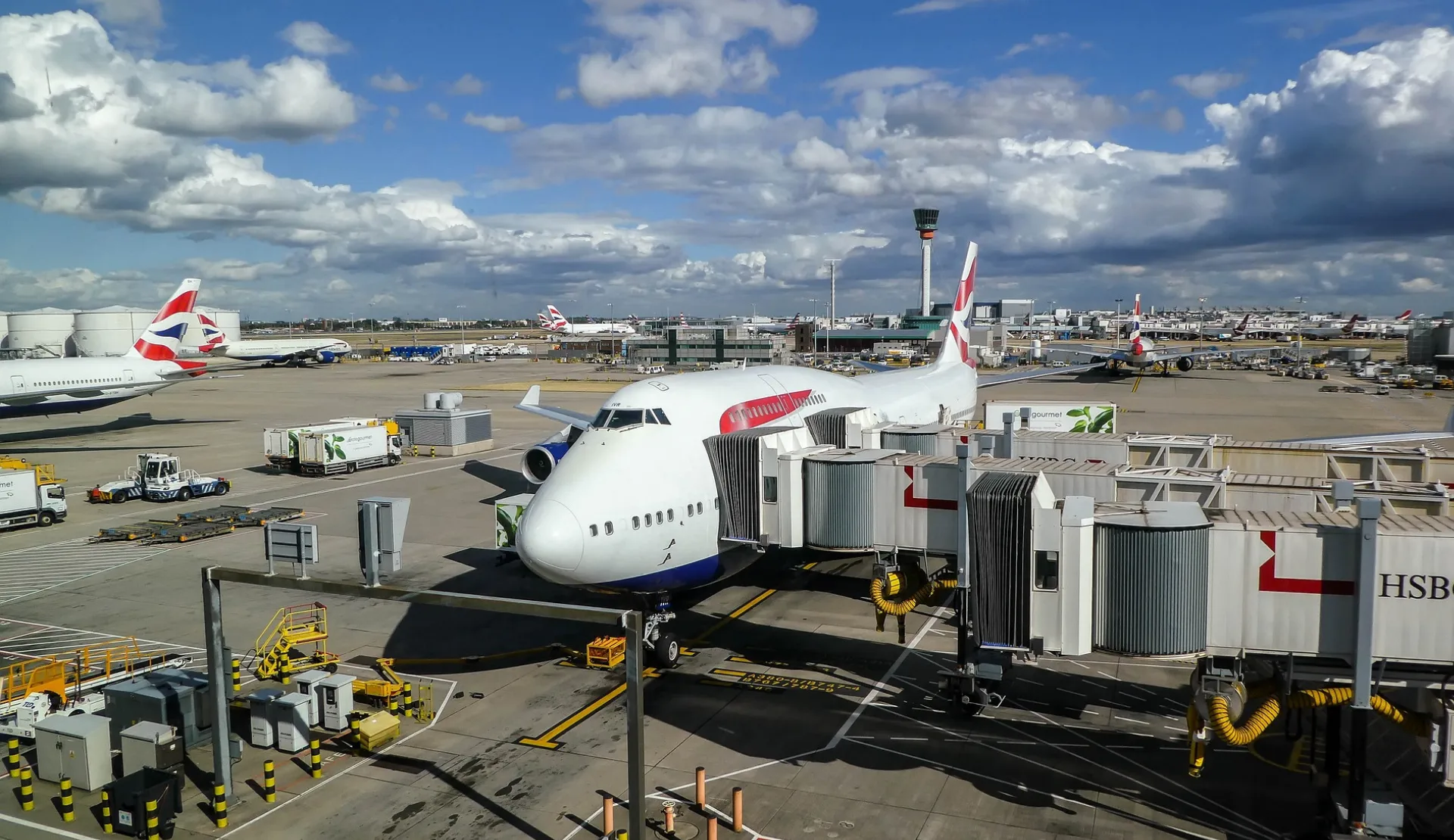 Flugzeug an der Fluggastbrücke am Heathrow Airport in London mit Kontrollturm im Hintergrund