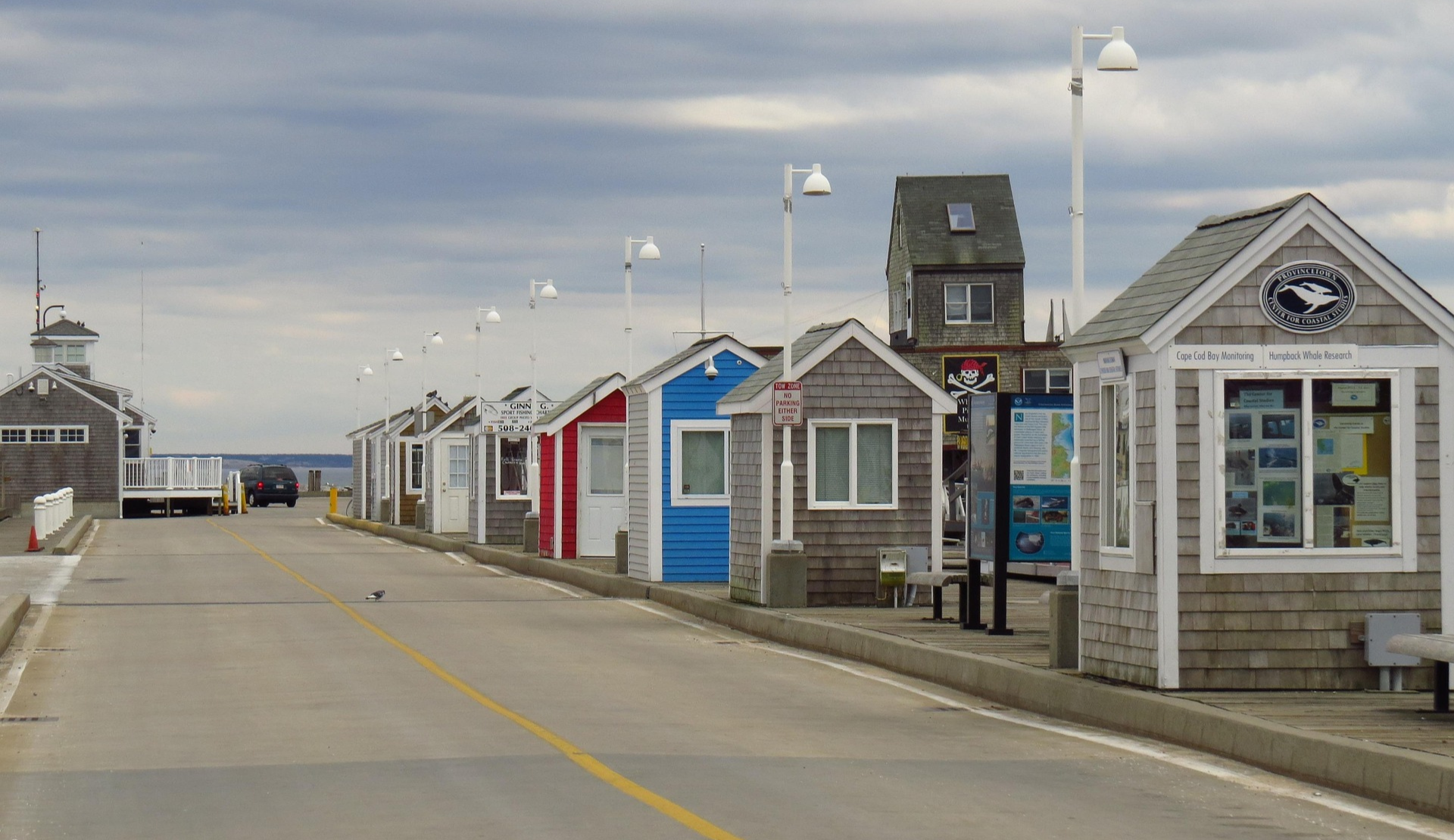 Reihe kleiner Holzhuetten entlang einer Hafenpromenade mit Blick aufs Meer an der Kueste von Cape Cod