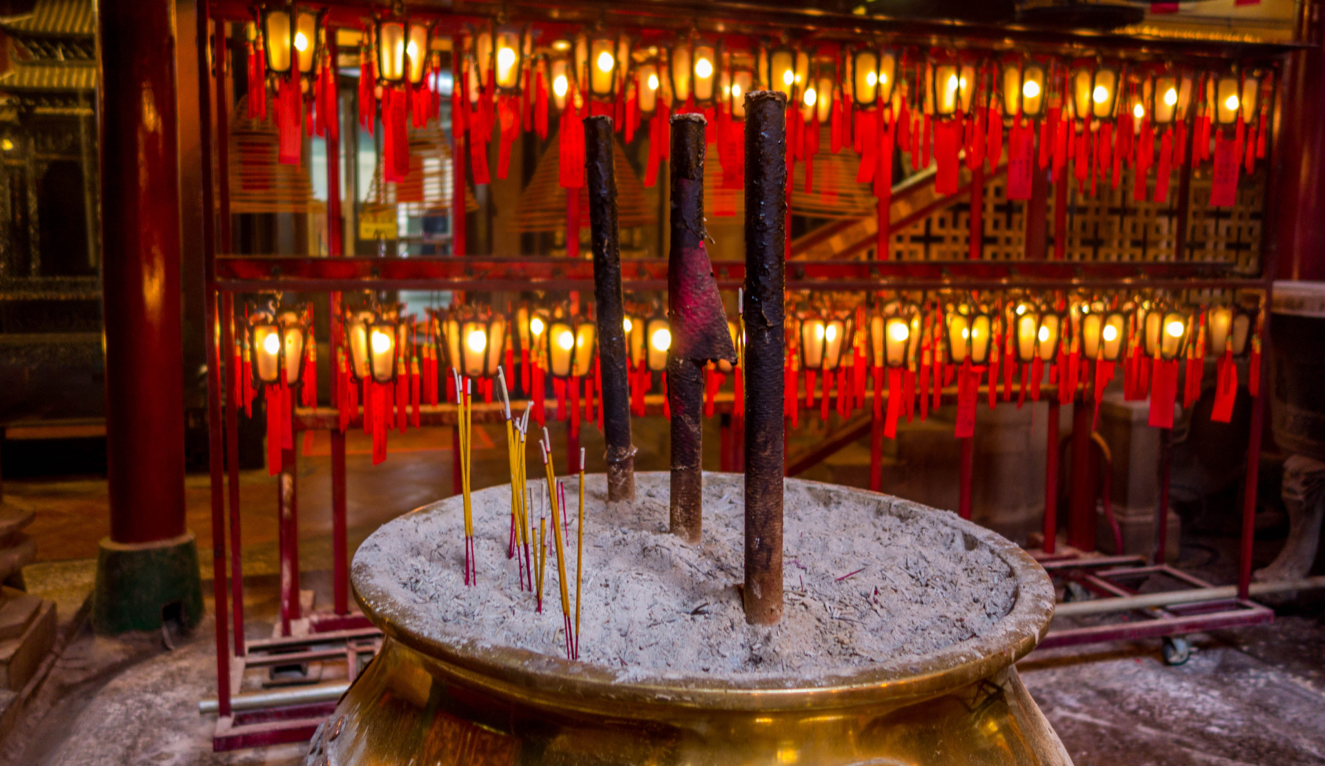 Brennende Räucherstäbchen und rote Gebetskerzen in einem traditionellen chinesischen Man Mo Tempel in Hongkong