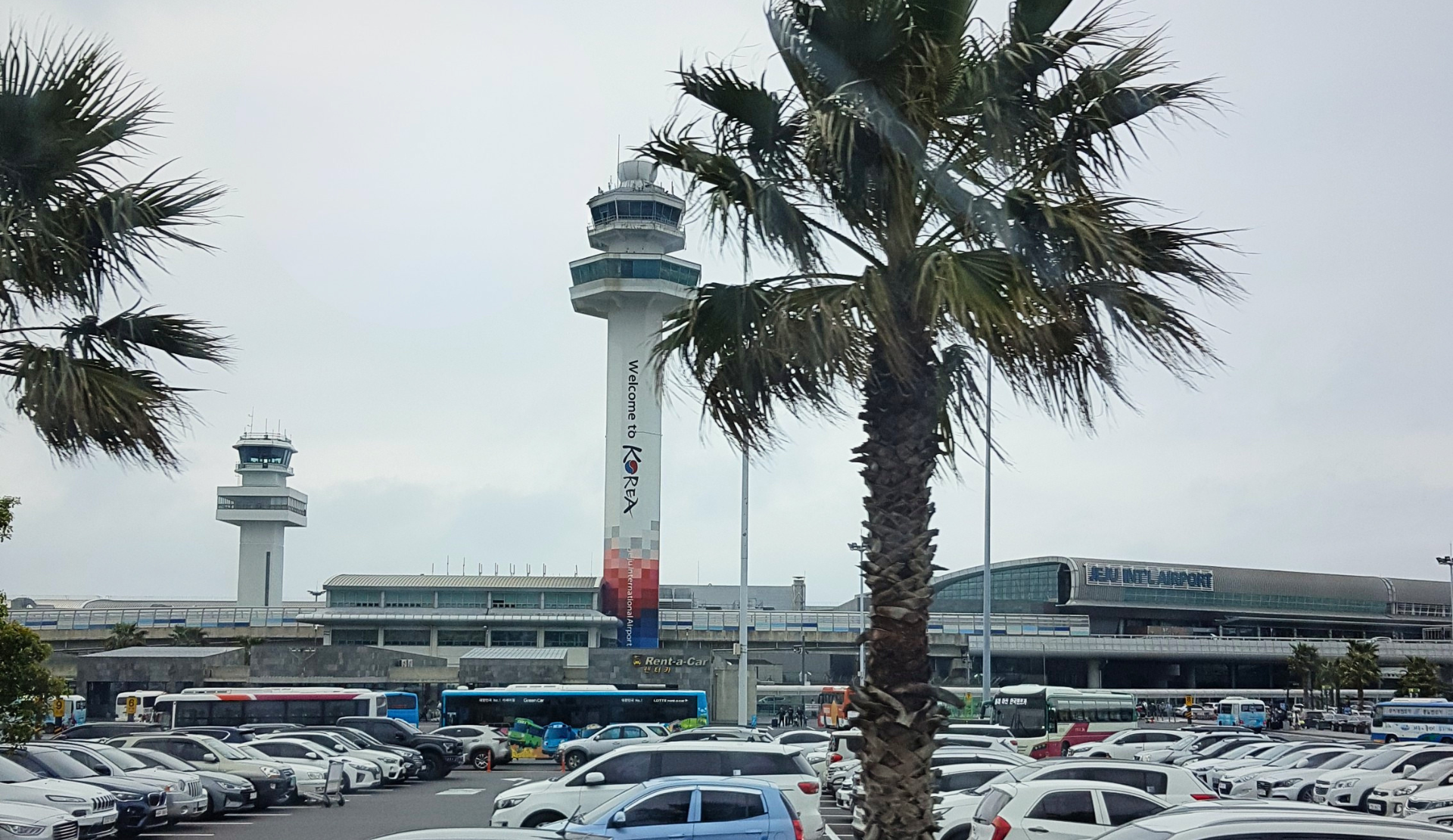 Jeju International Airport mit Palmen im Vordergrund und Kontrollturm auf Jeju Island Südkorea