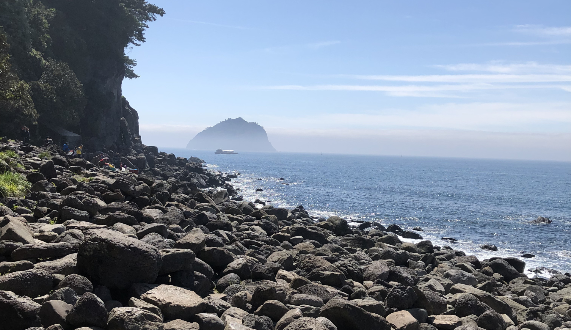  Lavafelsen an der Küste von Jeju Island Südkorea mit dem Seongsan Ilchulbong im Hintergrund