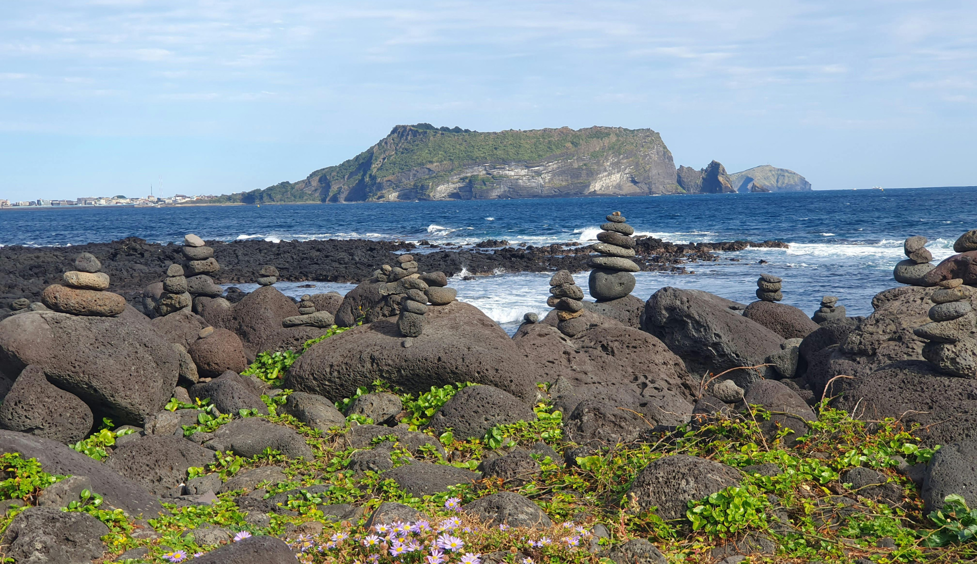 Schwarze Lavafelsen mit gestapelten Steinen an der Küste von Jeju Island Südkorea
