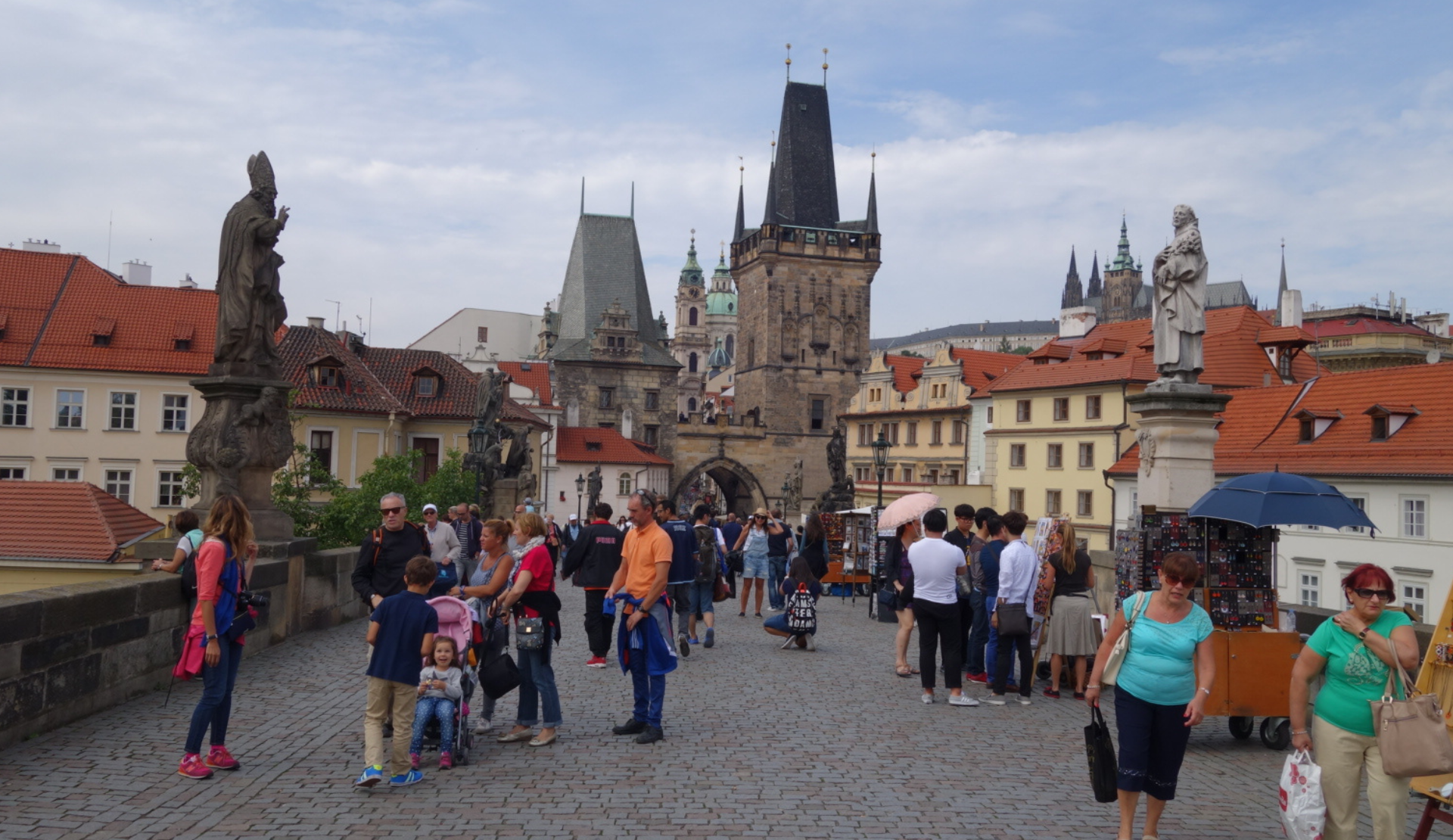 Blick über die Karlsbrücke in Prag mit Heiligenfiguren, Brückenturm und Besuchern