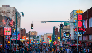 Menschen bummeln über die Beale Street in Memphis mit bunten Neonlichtern und Musikclubs