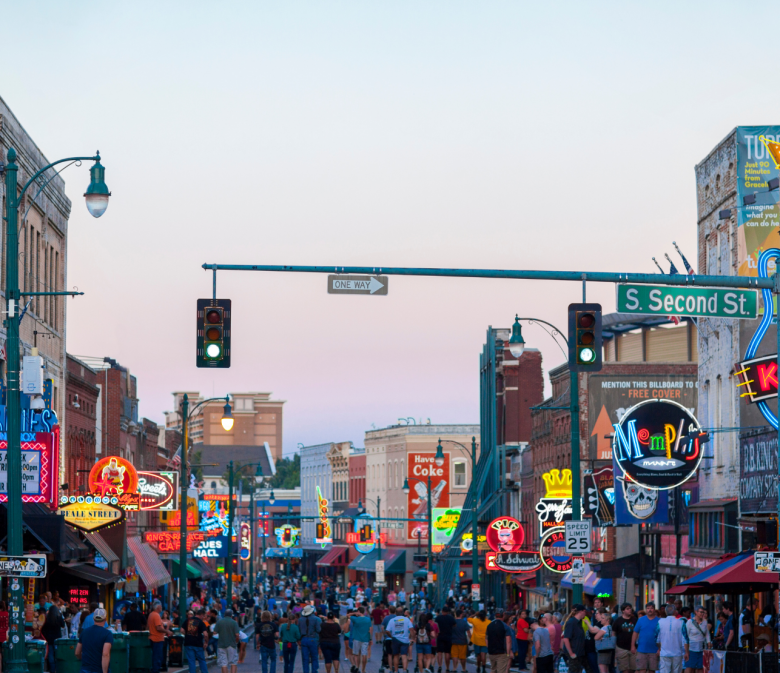 Menschen bummeln über die Beale Street in Memphis mit bunten Neonlichtern und Musikclubs