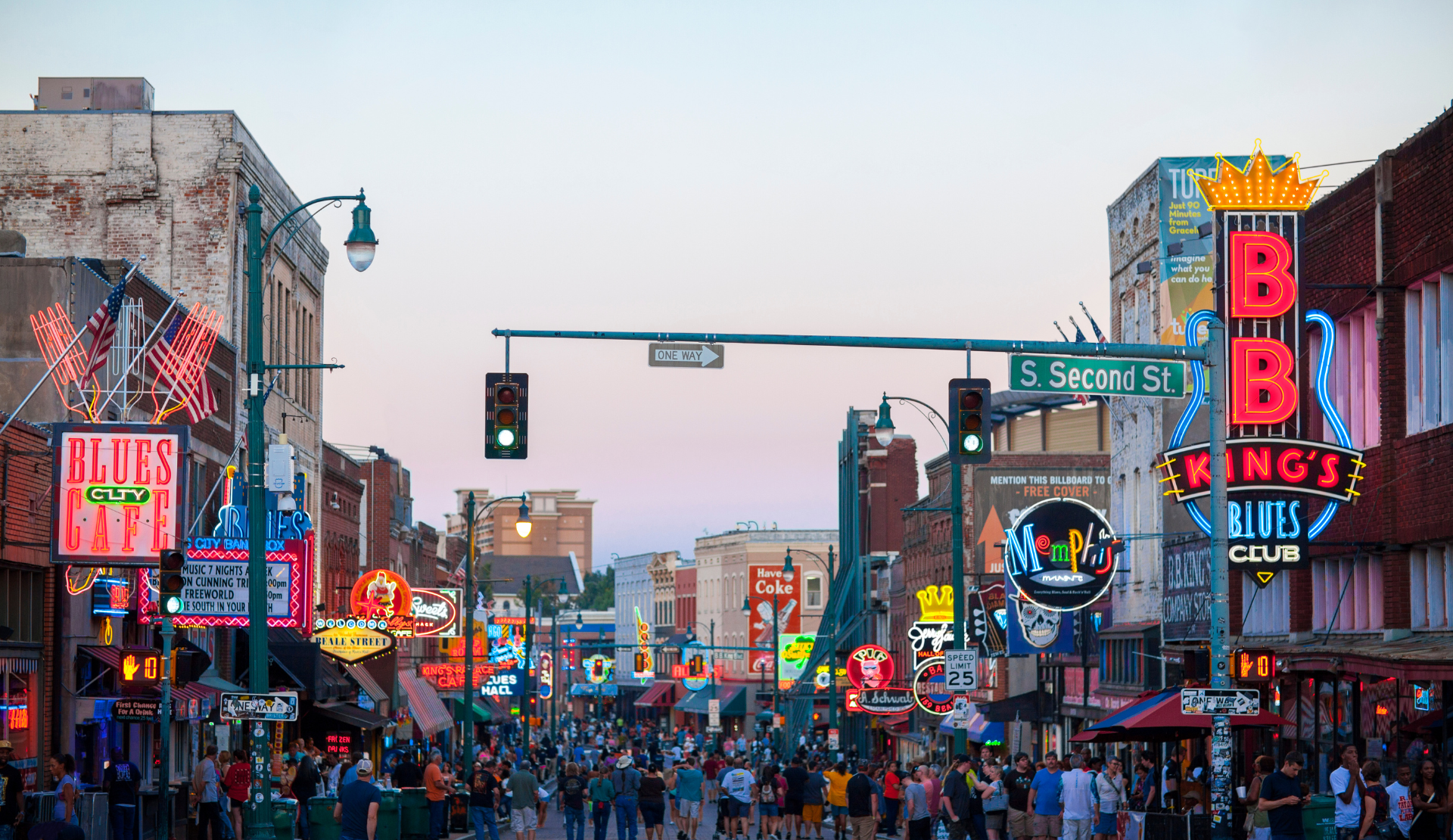 Menschen bummeln über die Beale Street in Memphis mit bunten Neonlichtern und Musikclubs