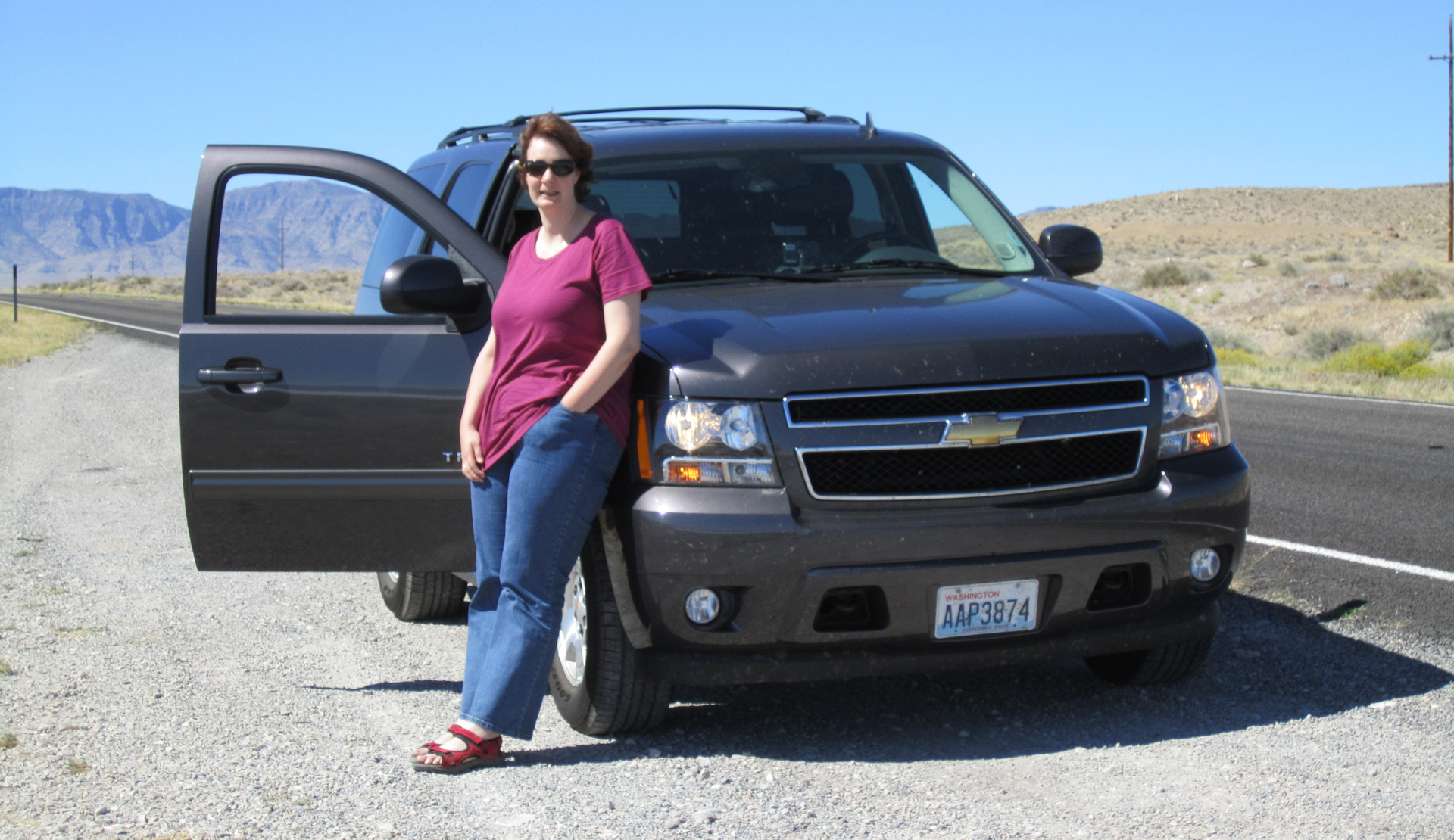 Frau steht vor eine Auto auf einem Roadtrip durch die USA