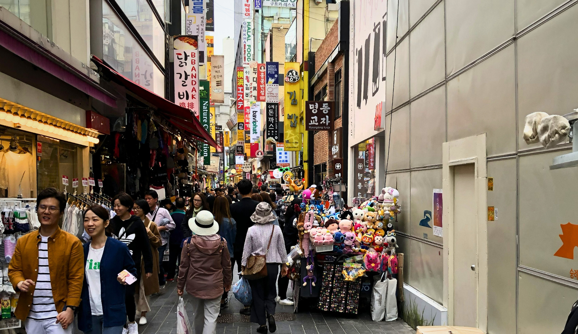 Belebte Einkaufsstraße in Myeong-dong Seoul mit bunten koreanischen Schildern, Geschäften und vielen Passanten
