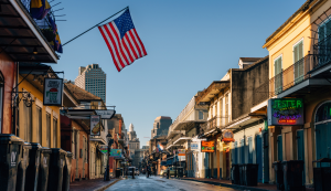 Straßenszene auf der Bourbon Street in New Orleans mit Balkonen und US-Flagge