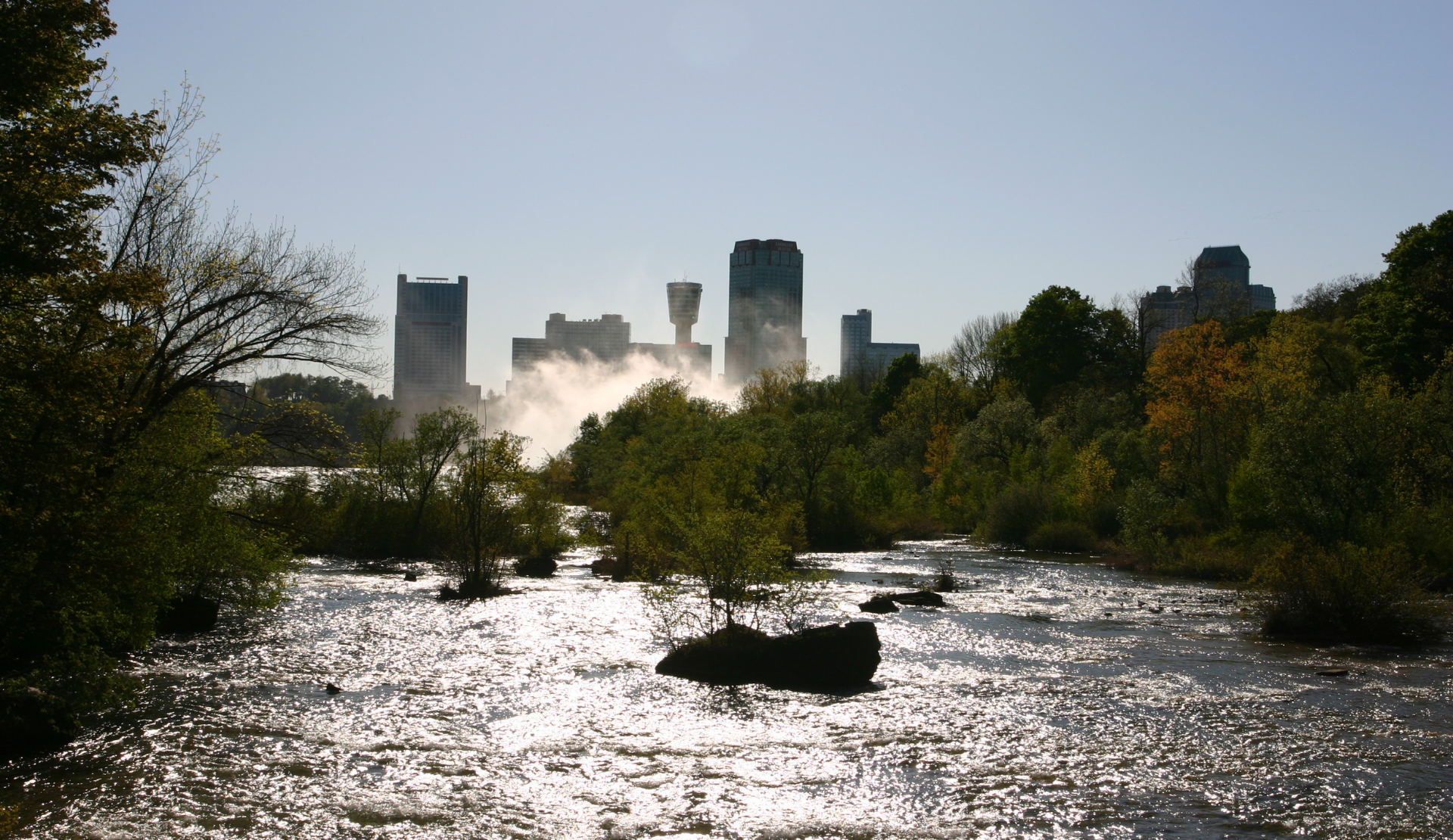 Blick auf die Niagarafälle mit Skyline im Hintergrund und Fluss im Vordergrund