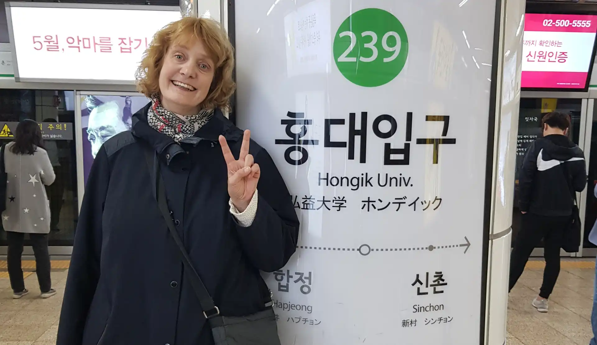 Peggy an der U-Bahn Station Hongik University in Seoul mit koreanischen Schriftzeichen im Hintergrund