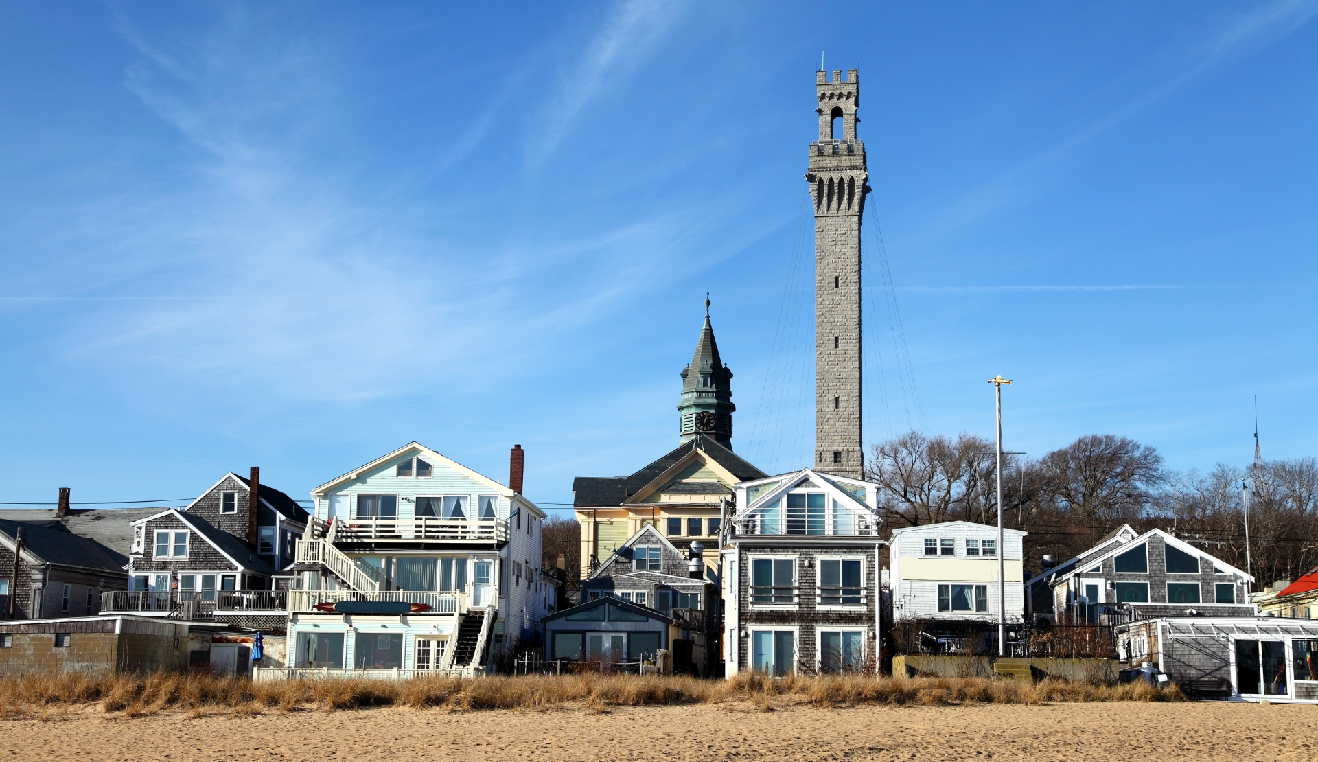 Strandhaeuser in Provincetown mit dem Pilgrim Monument im Hintergrund an der Kueste von Cape Cod