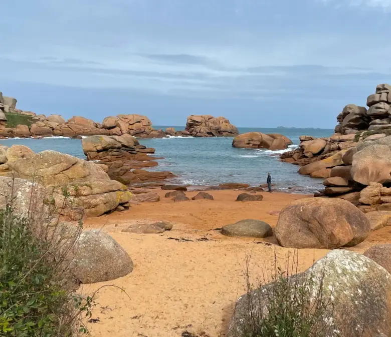 Sandstrand zwischen rosa Granitfelsen in Ploumanac'h mit Blick auf den Leuchtturm Phare de Mean Ruz