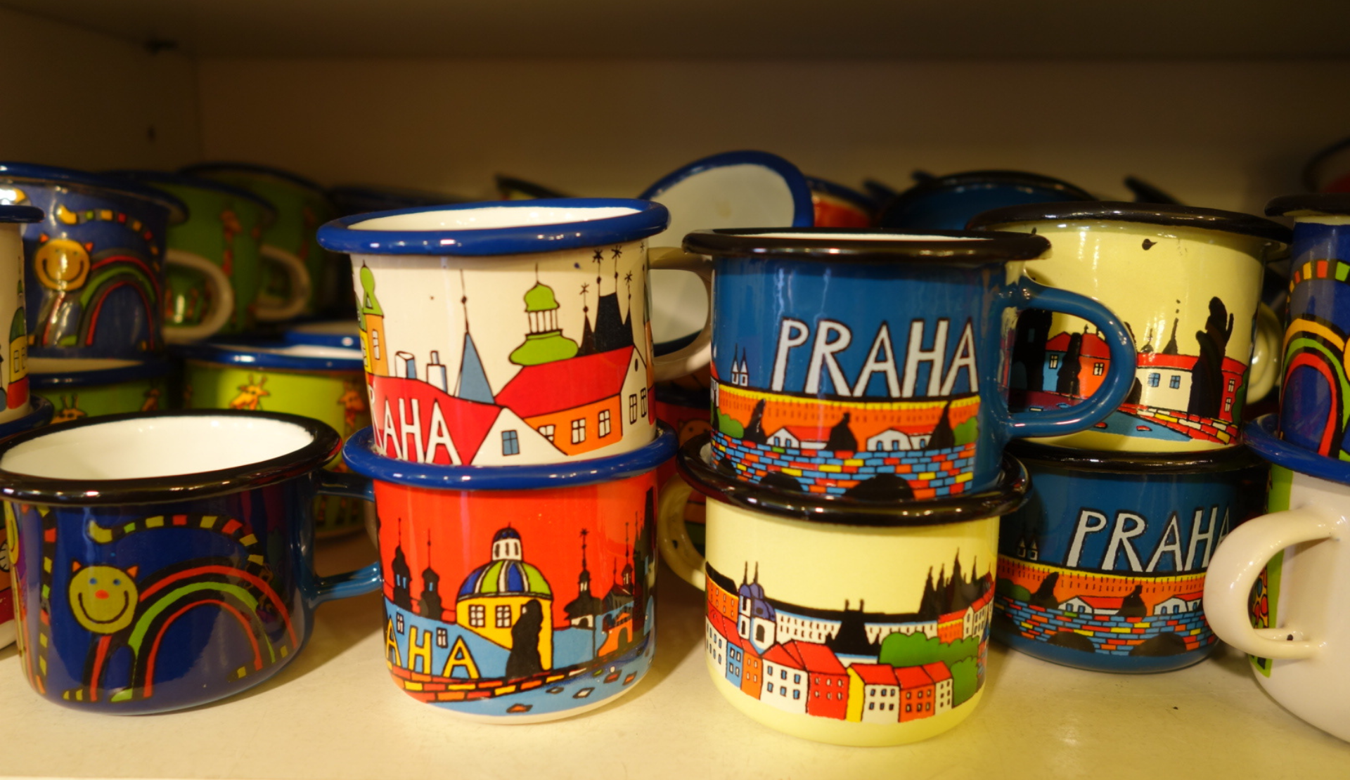 Bunte Souvenirbecher mit Prag-Motiven und Praha-Aufdruck in einem Souvenirladen