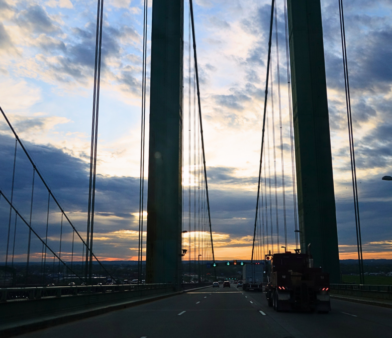 Roadtrip USA über eine Hängebrücke bei Sonnenuntergang, Seile und Pylon im Gegenlicht