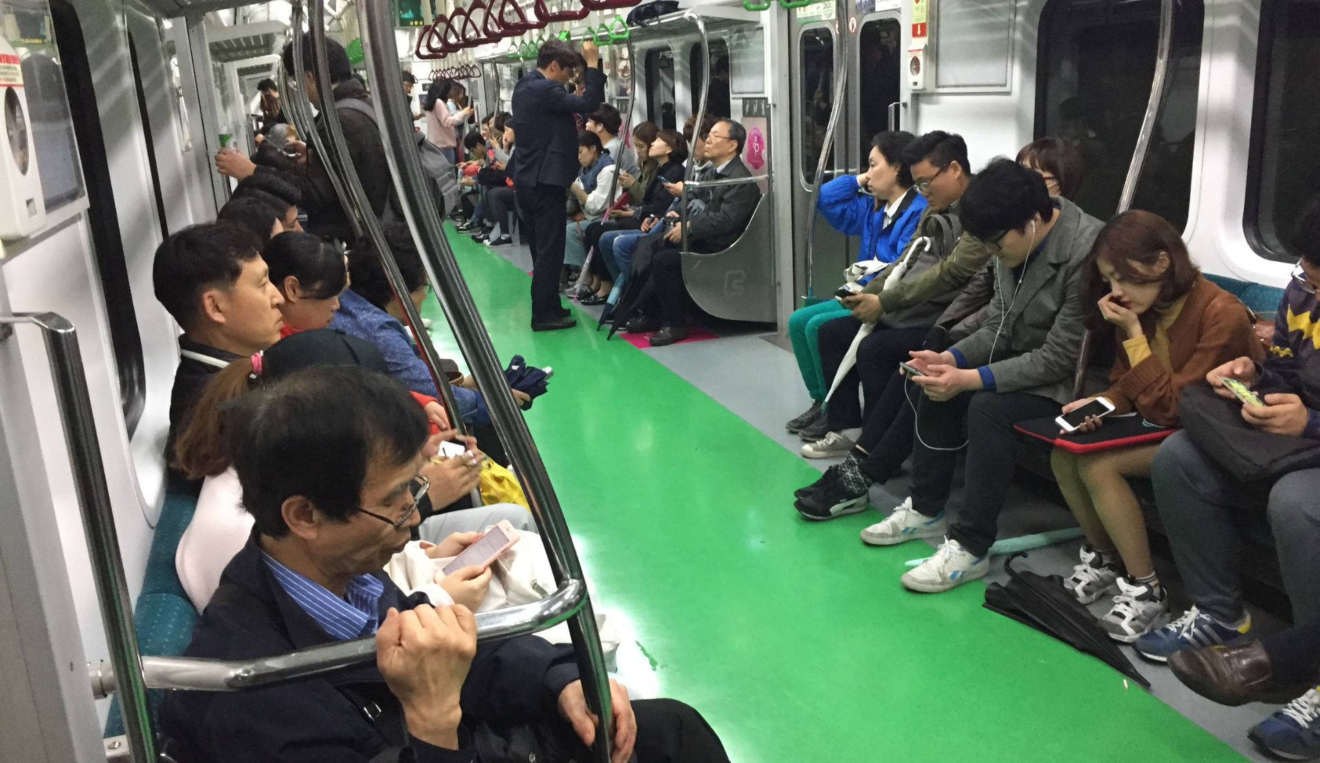 Innenraum der Seoul Metro mit Fahrgästen auf grünen Sitzen