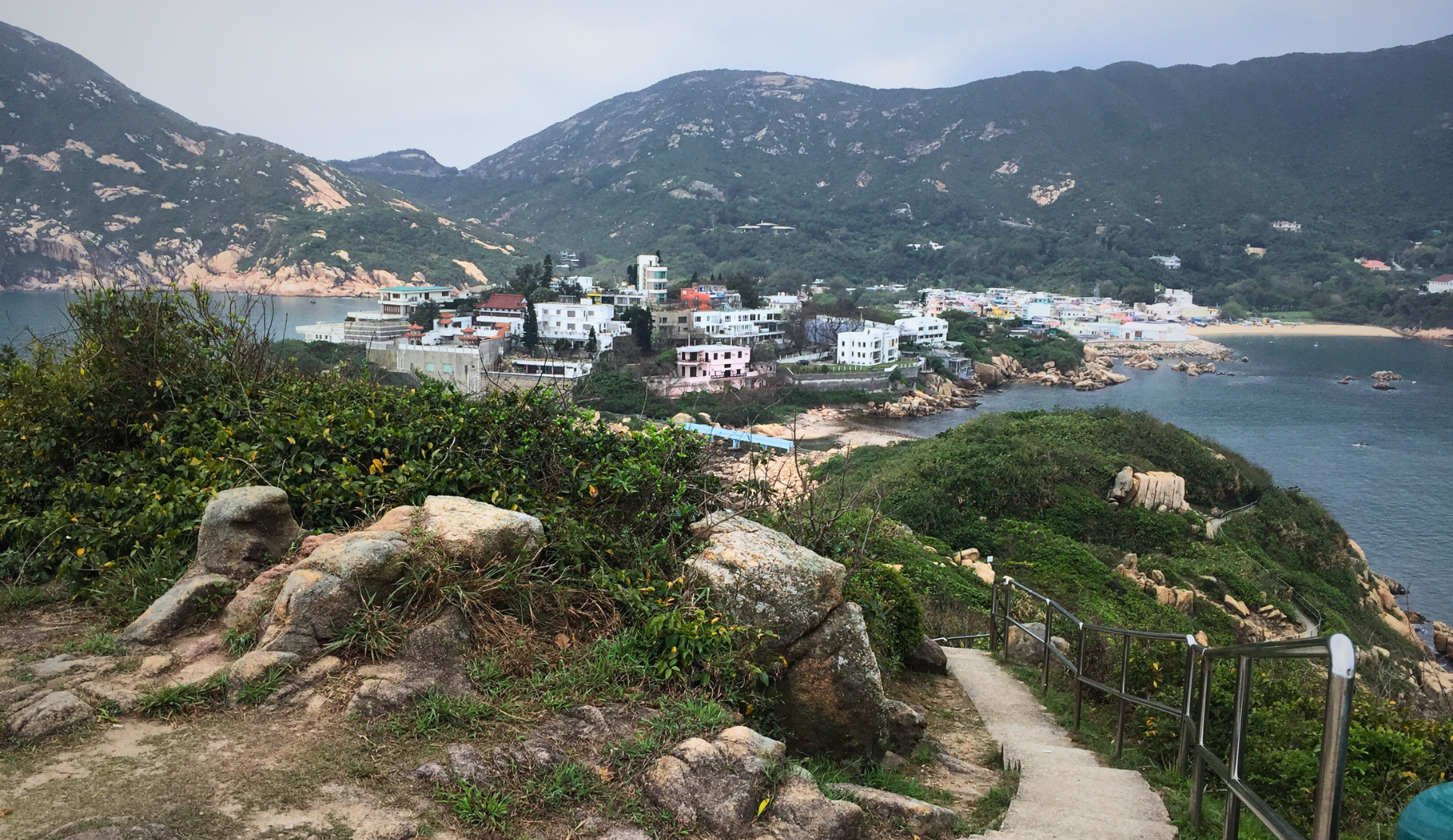 Wanderweg in Shek O, Hongkong, mit Panoramablick auf den Strand, türkisfarbenes Meer und grüne Berghänge