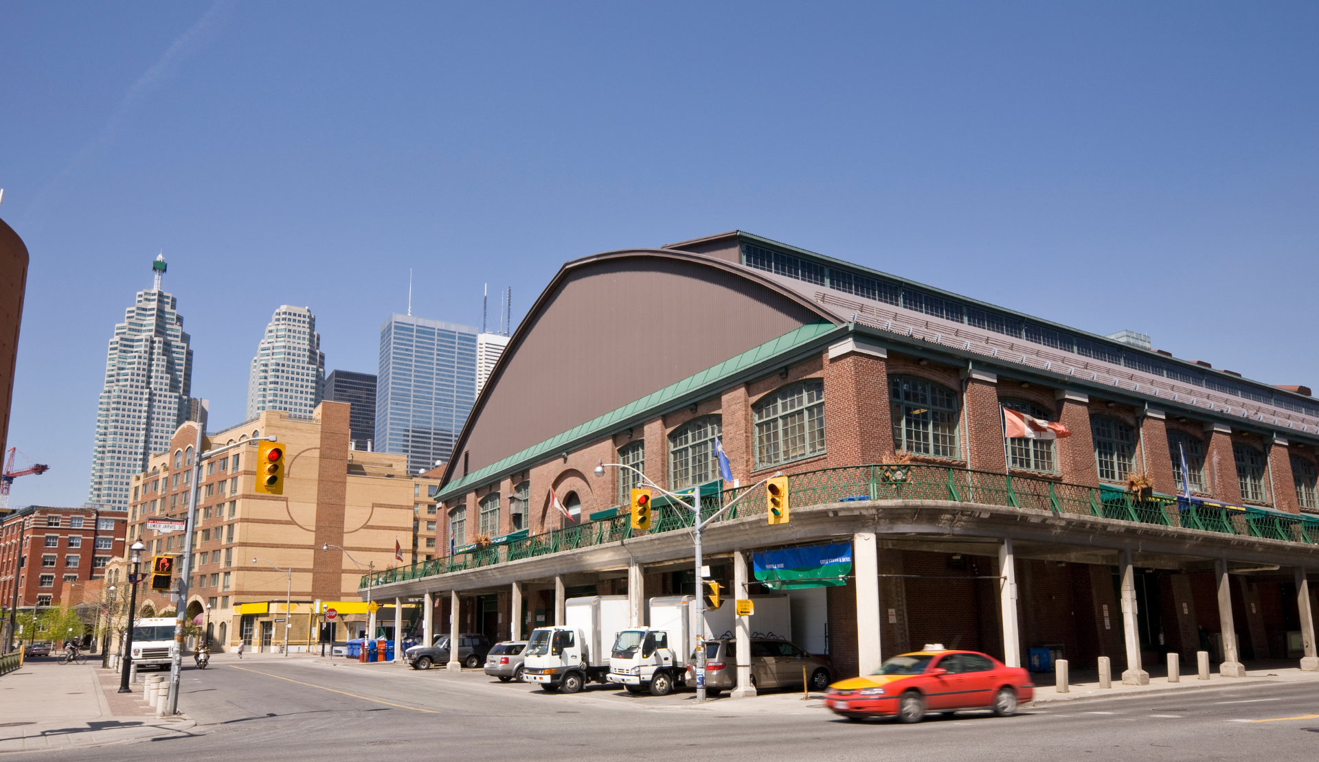 Außenansicht des St. Lawrence Market in Toronto mit rotem Backsteingebäude und Skyline im Hintergrund