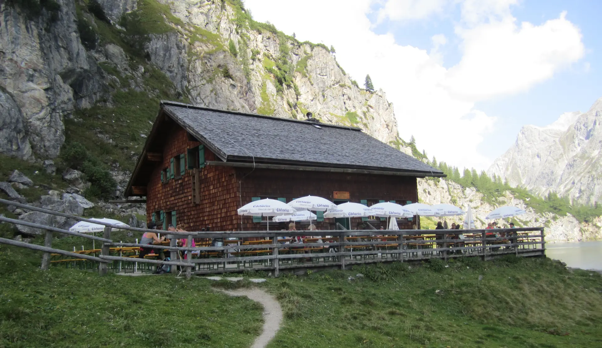 Tappenkarseealm mit Holzhaus, Terrasse und Sonnenschirmen direkt am Ufer des Tappenkarsees