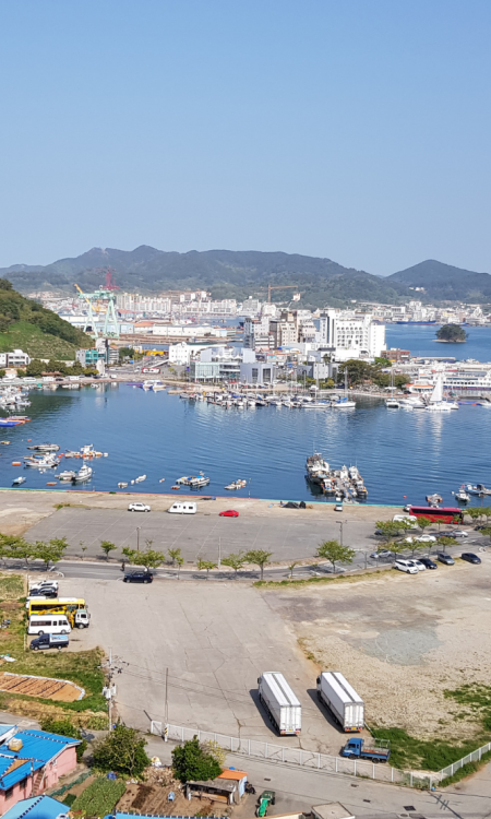 Panoramablick auf den Hafen von Tongyeong mit Stadtkulisse und Bergen im Hintergrund, Südkorea
