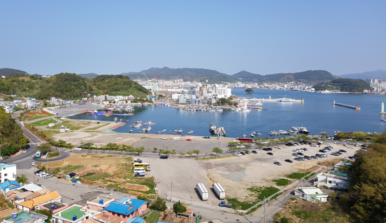 Panoramablick auf den Hafen von Tongyeong mit Stadtkulisse und Bergen im Hintergrund