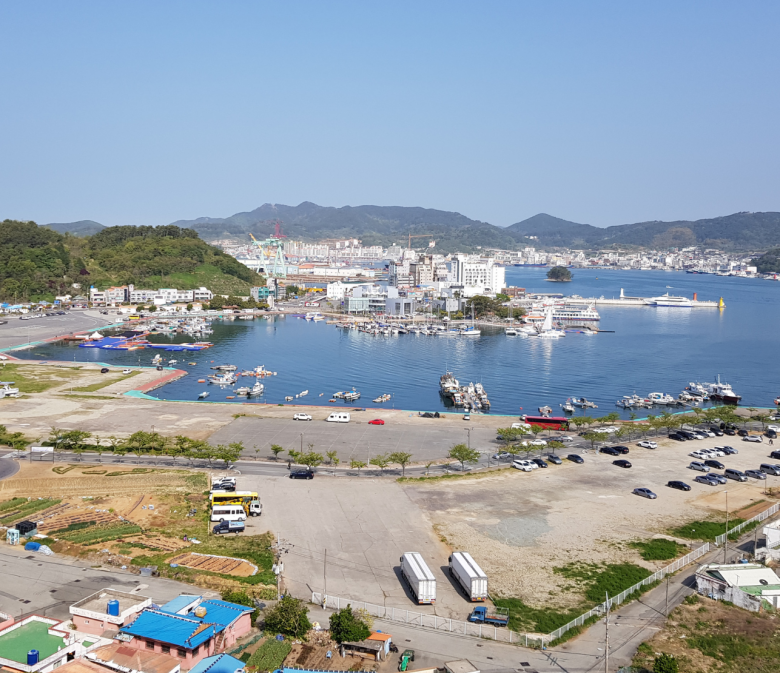 Panoramablick auf den Hafen von Tongyeong mit Stadtkulisse und Bergen im Hintergrund, Südkorea