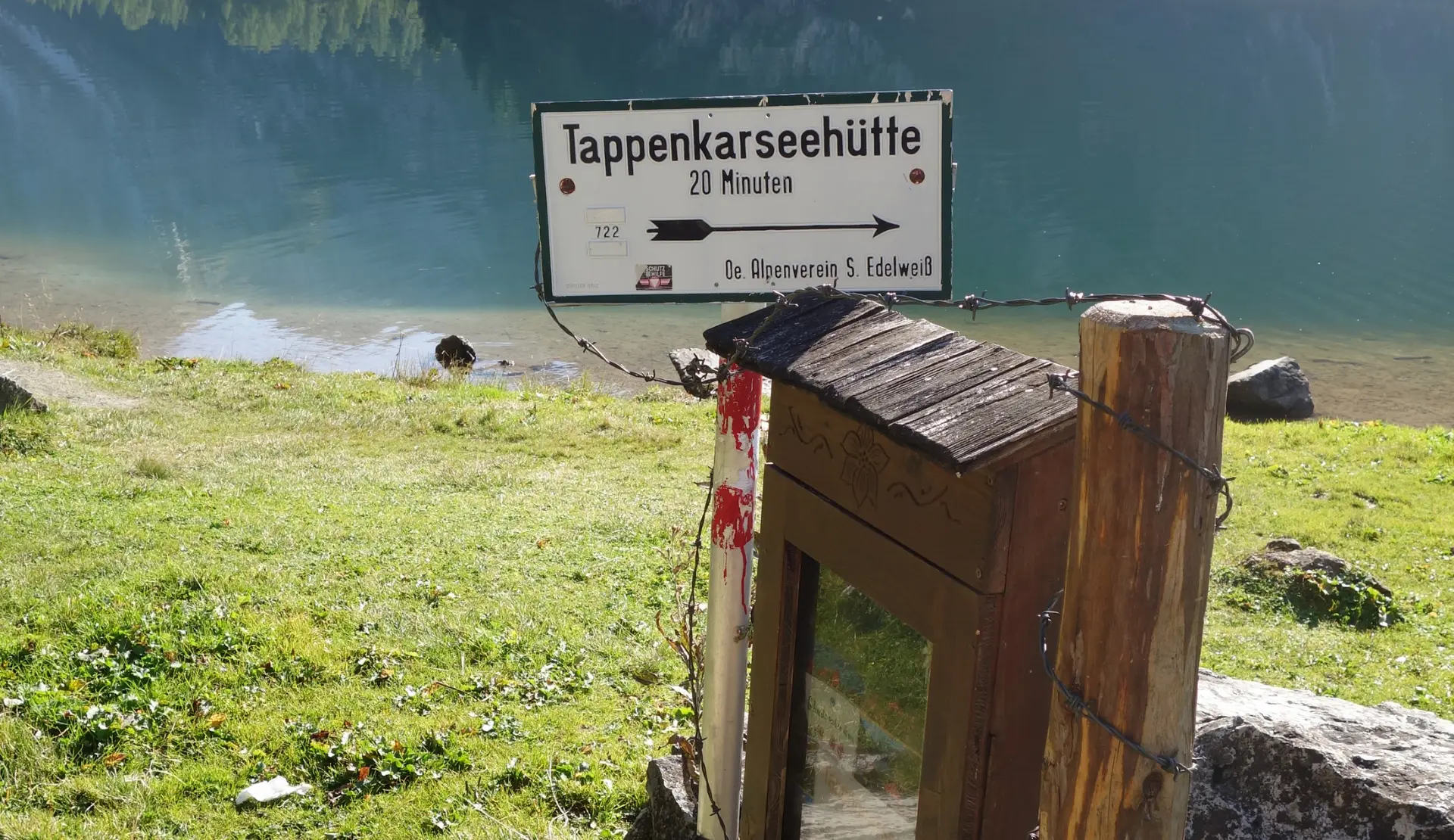 Holzwegweiser zur Tappenkarseehütte mit Wegnummer 722 und 20 Minuten Gehzeit am Ufer des Tappenkarsees