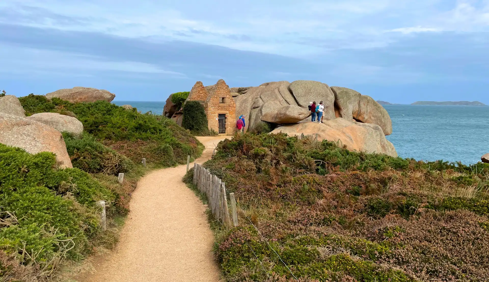 Wanderweg auf dem Zöllnerpfad GR34 bei Ploumanac'h zwischen rosa Granitfelsen mit Blick aufs Meer